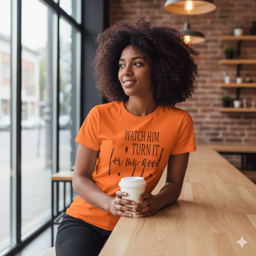 Woman in an orange t-shirt holding a coffee cup in a cafe.