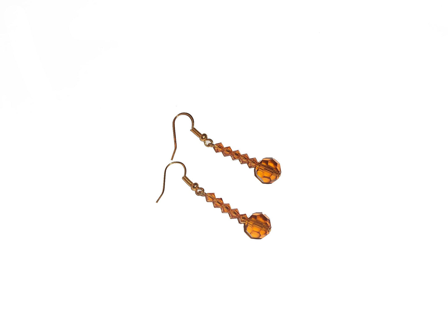 A pair of handcrafted topaz dangle earrings with bicone and round crystals, suspended from gold French ear wire hooks.