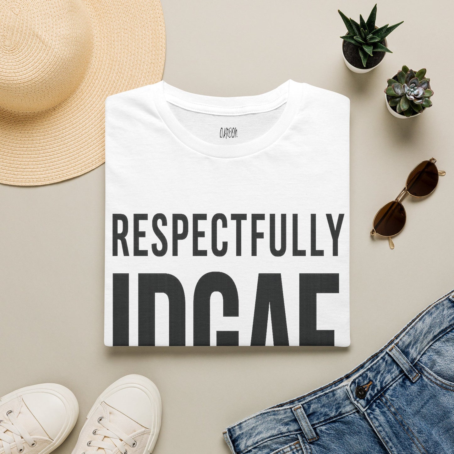 White t-shirt with 'RESPECTFULLY INGAE' text, surrounded by casual items on a beige surface.