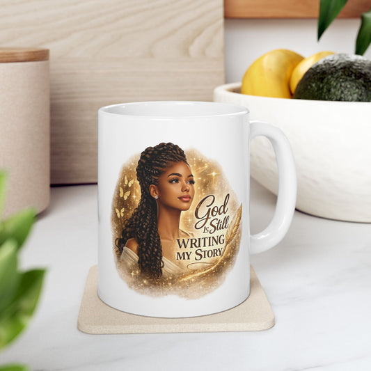 White mug with a design of a woman and text 'God is Still Writing My Story' on a coaster.