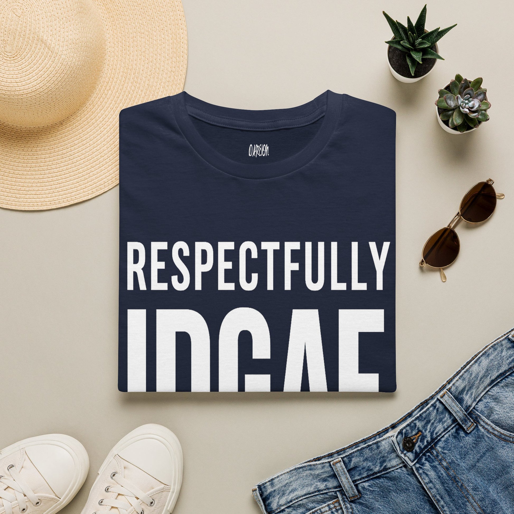 Navy blue t-shirt with 'RESPECTFULLY INDIE' text on a beige surface with casual items.