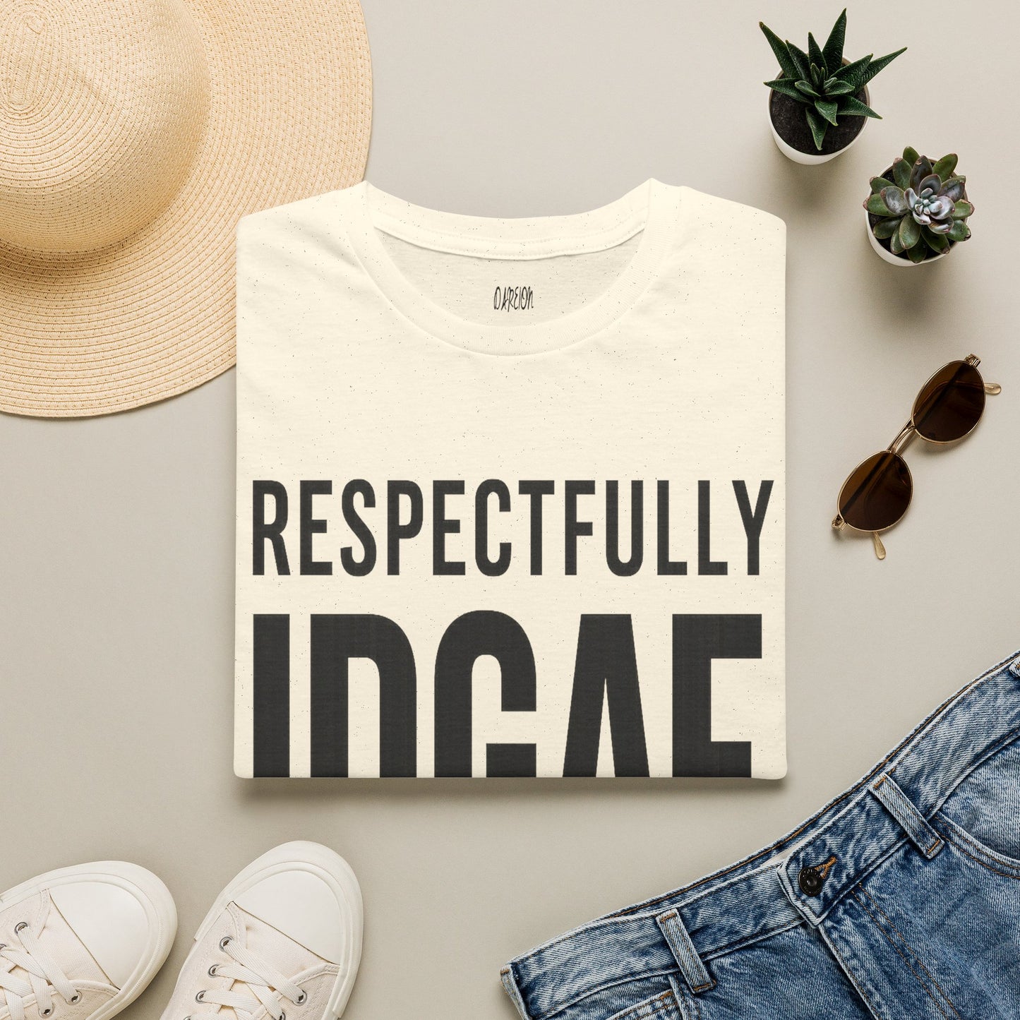 T-shirt with 'RESPECTFULLY IDGAF' text, surrounded by a hat, sunglasses, and jeans on a light surface.