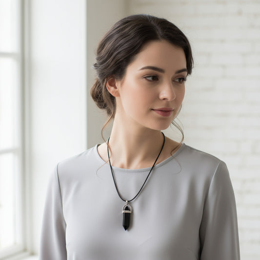 A black wax rope necklace with a silver chain and a teardrop-shaped crystal pendant.