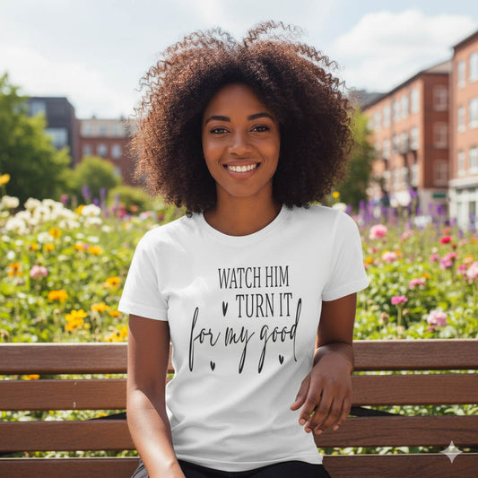 Woman wearing a white t-shirt with text, sitting on a bench in a park.