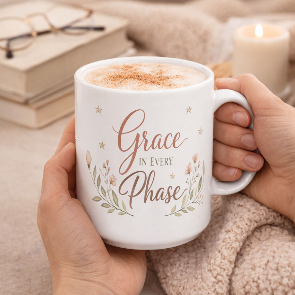 Person holding a 15 oz mug with 'Grace in Every Phase' text and a floral design.