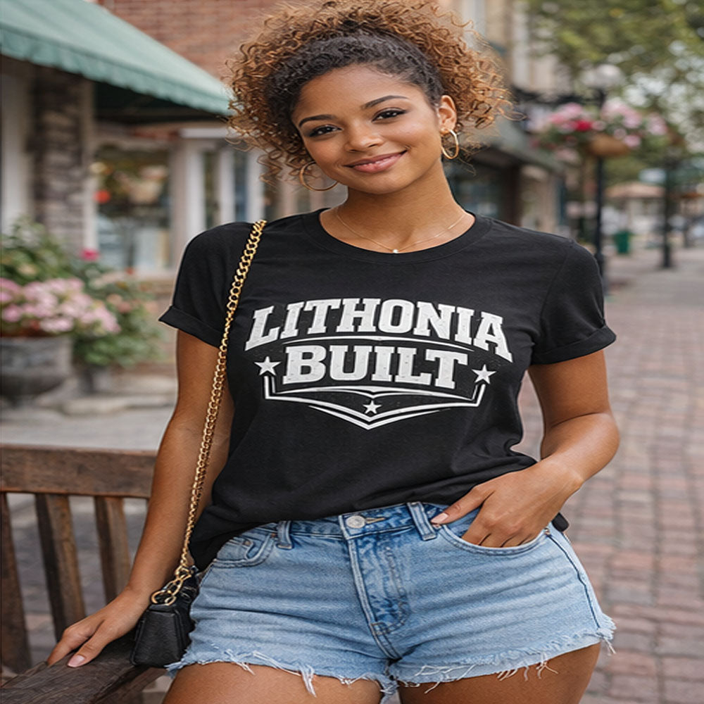 Woman wearing a black t-shirt with 'Lithonia Built' text, standing outdoors.