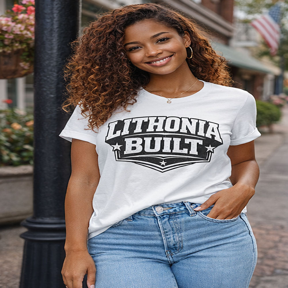 Woman wearing a white t-shirt with 'Lithonia Built' text, standing on a street.