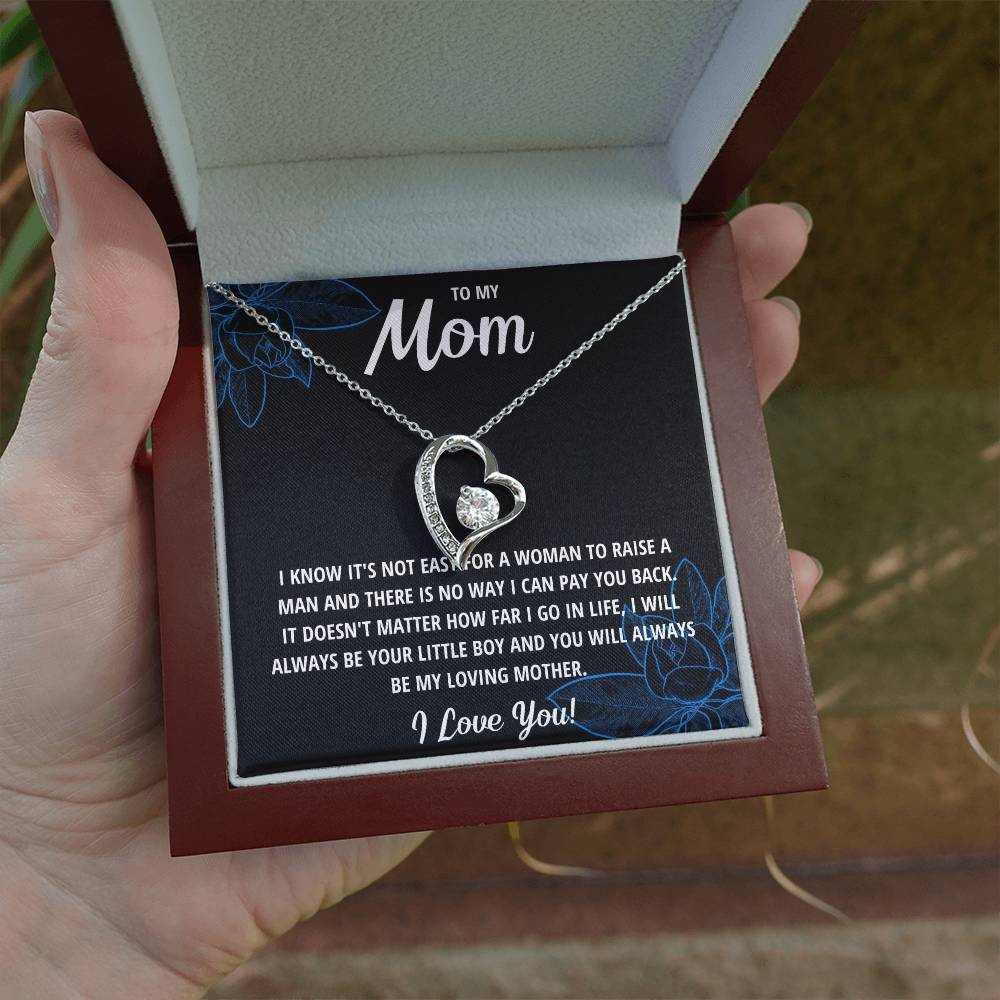 Necklace with heart design held in a box with a message for 'Mom' on a blurred background