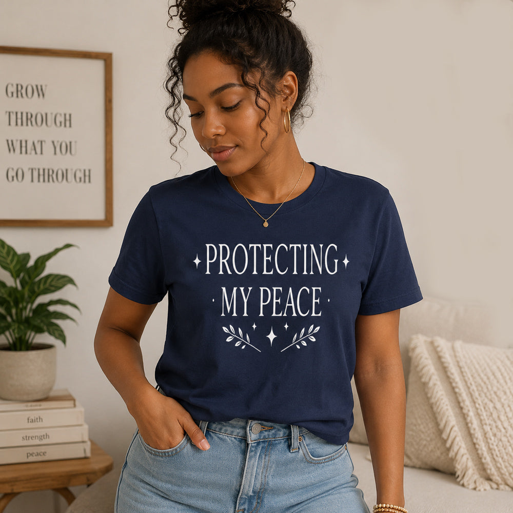 Woman wearing a navy blue t-shirt with 'PROTECTING MY PEACE' text in a home setting.