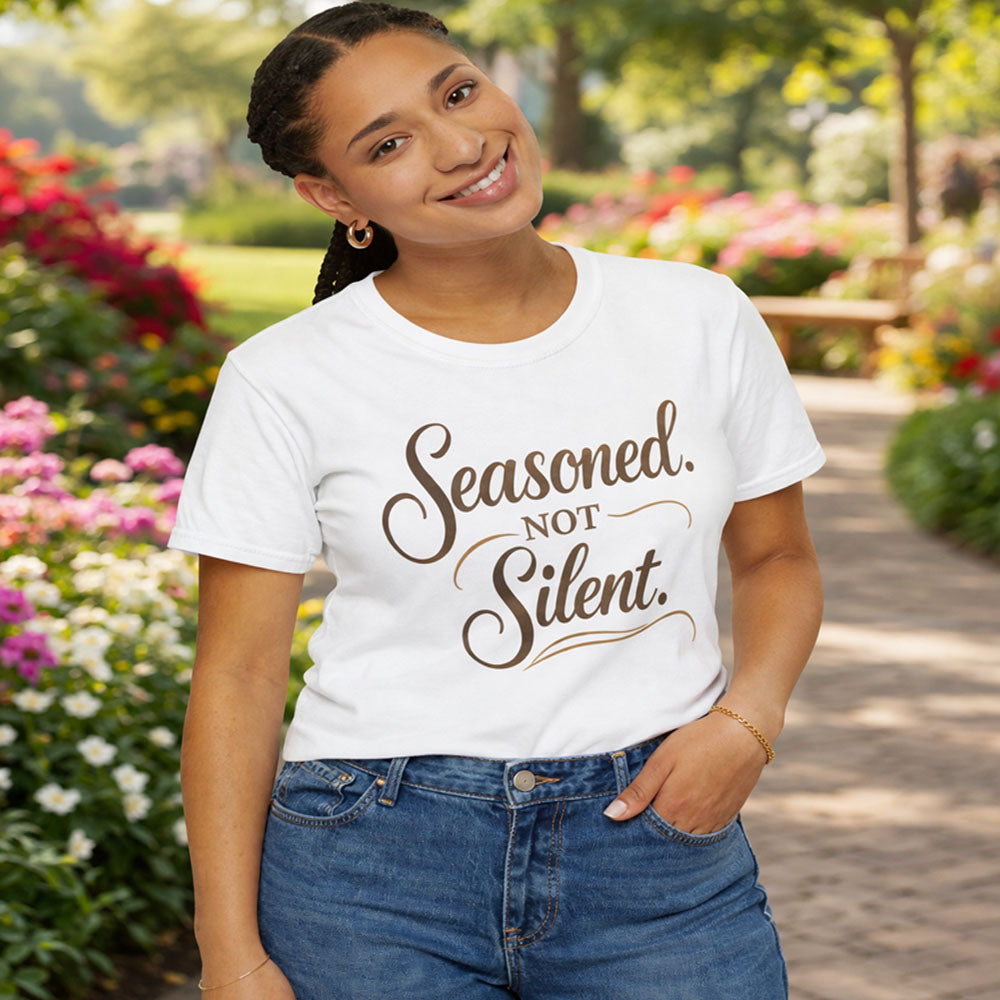 Person wearing a white t-shirt with 'Seasoned. Not Silent.' text in a garden setting